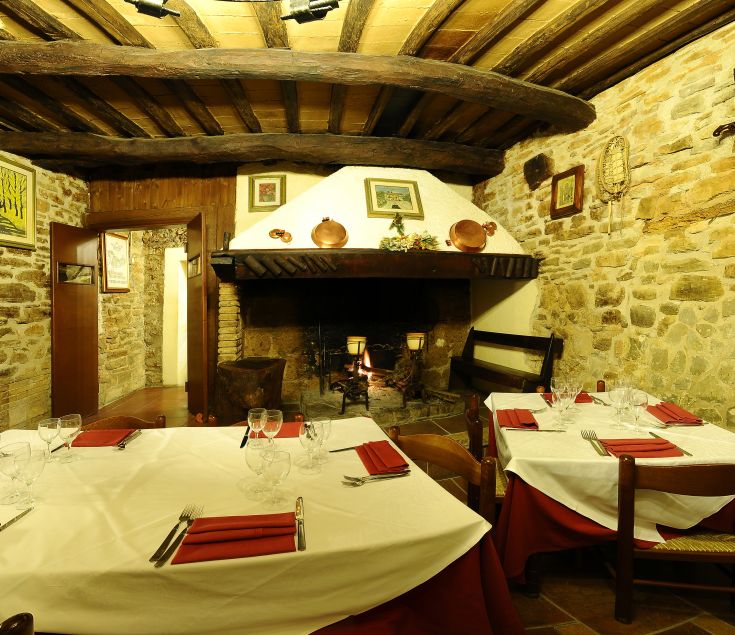 Un ristorante accogliente, dotato di un camino e di tavoli ben apparecchiati.