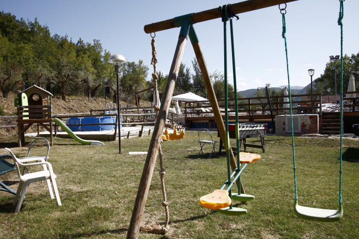 Spazio ludico immerso nel verde, dotato di altalene e scivolo, adatto a famiglie in un contesto sereno.