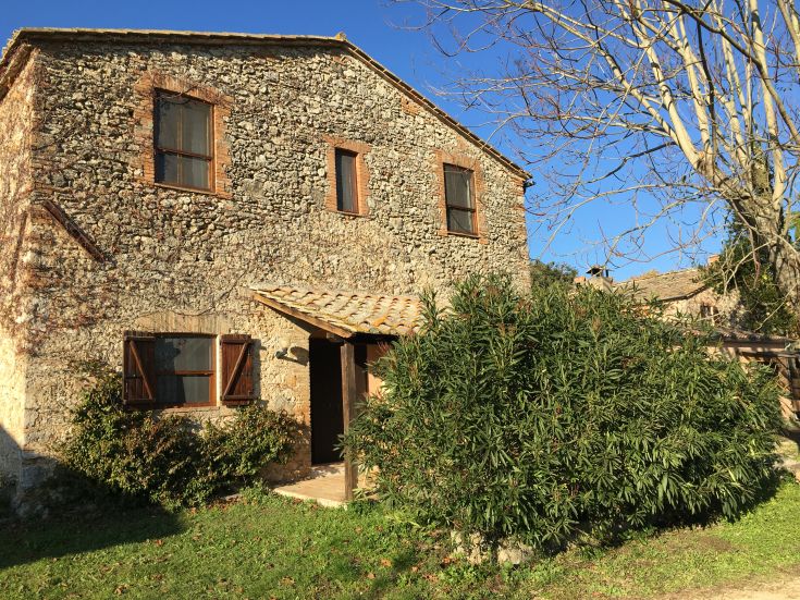 Edificio storico in pietra, circondato da spazi verdi e oliveti, nel caratteristico paesaggio umbro.