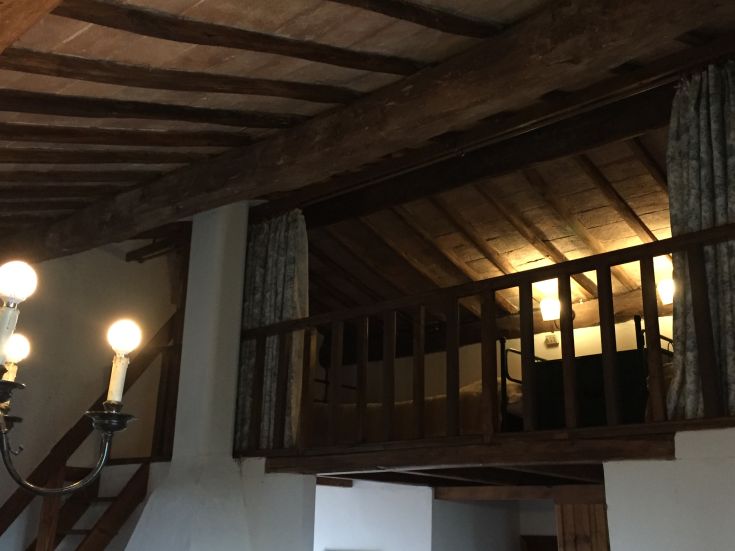 Ambiente di un agriturismo caratterizzato da un soppalco e un lampadario semplice.