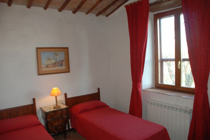 Stanza semplice con letti singoli, colori caldi e decorazioni sobrie.