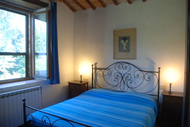 Camera ben illuminata con letti in ferro battuto, arredamento essenziale e confortevole.