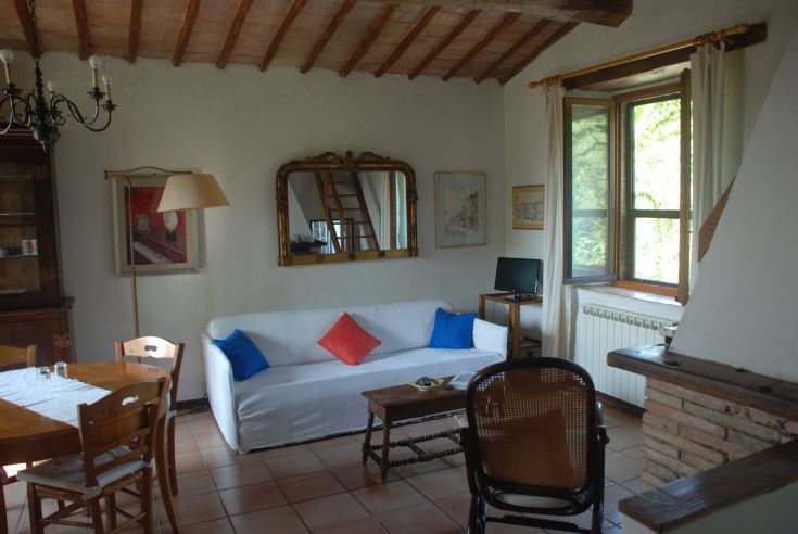 Soggiorno semplice con divano bianco e arredi tradizionali, perfetto per momenti di tranquillità.