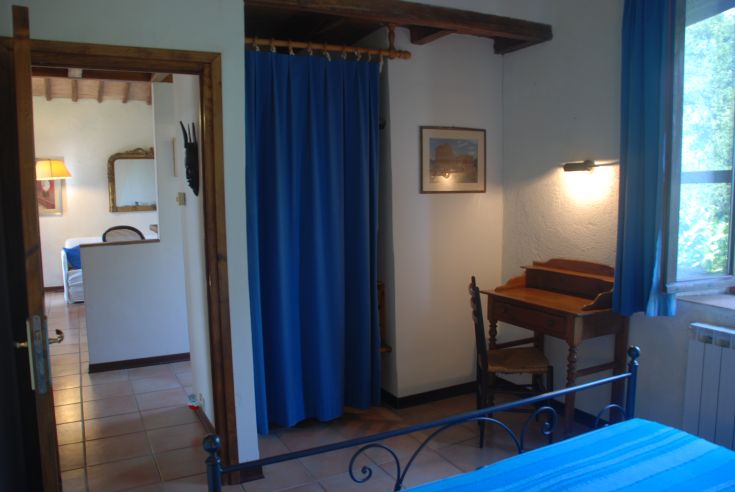 Camera semplice con letto matrimoniale, scrivania e tendaggi blu, creata per un ambiente confortevole.