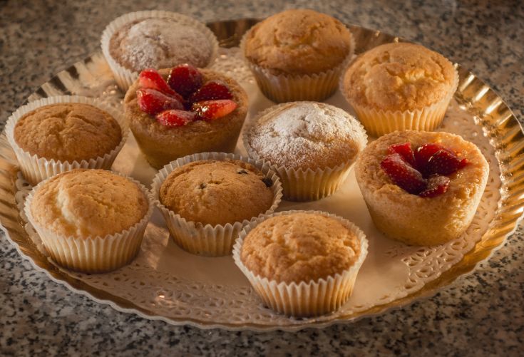 Varietà di muffin decorati con frutta e una leggera spolverata di zucchero a velo.
