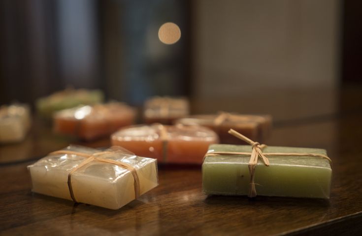 Saponi artigianali di diverse colorazioni, sistemati con cura su un tavolo di legno.