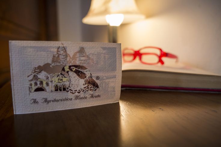 Un cartoncino informativo dell'agriturismo situato nella campagna umbra, circondato da un ambiente naturale.