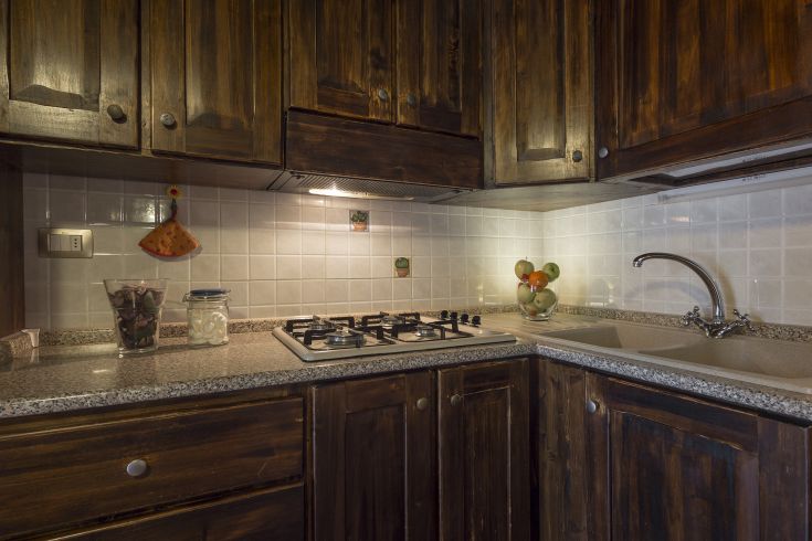 Cucina in legno scuro con piano in granito e dettagli semplici, adatta per un ambiente familiare.