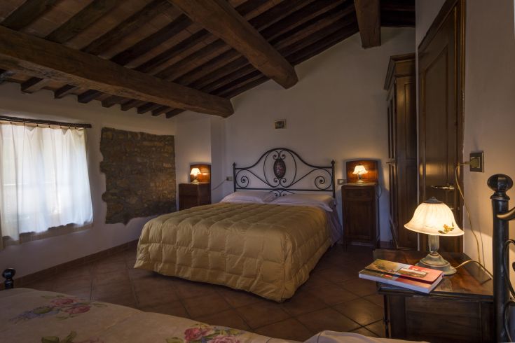 Camera spaziosa con letto matrimoniale, travi in legno a vista e mobili in legno, perfetta per un soggiorno tranquillo.