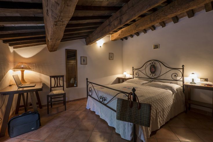 Camera semplice in agriturismo, dotata di letto matrimoniale e mobili in legno. Un luogo tranquillo per riposare.