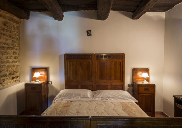 Camera accogliente con letto matrimoniale in legno e mobili in stile rustico, piacevole e funzionale.