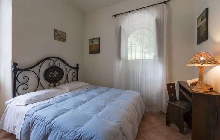 Camera confortevole con letto matrimoniale e finestre che si affacciano su un paesaggio naturale, perfetta per un soggiorno tranquillo.