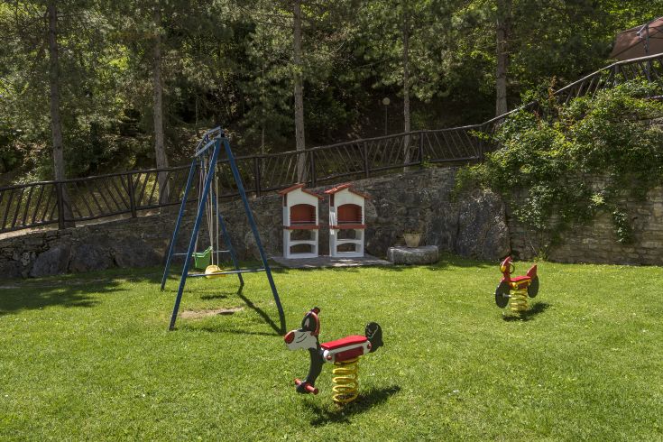 Un parco giochi circondato da alberi, con altalene e giochi a molla, perfetto per il divertimento dei più piccoli.