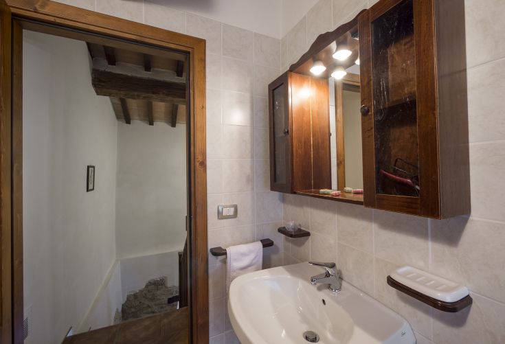 Un bagno semplice con armadietti in legno e specchi, ben illuminato e confortevole.