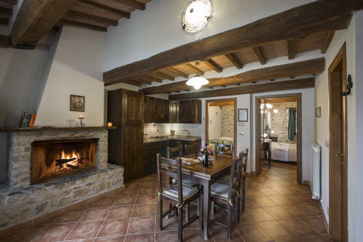 Cucina calorosa con tavolo e camino, caratterizzata da elementi in legno. Ideale per un soggiorno rilassante.
