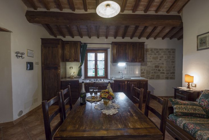 Cucina in legno semplice e accogliente, con un ampio tavolo e panorama su un giardino ben curato.