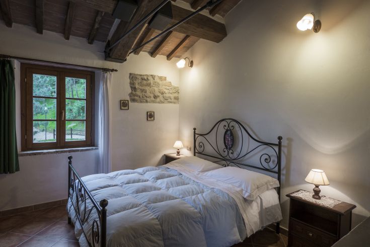 Camera semplice con letto matrimoniale e panorama sul verde circostante.