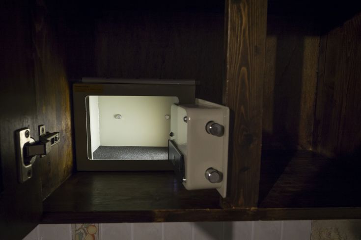 Un mobile con una cassaforte aperta, illuminata internamente, si integra con il legno scuro circostante.