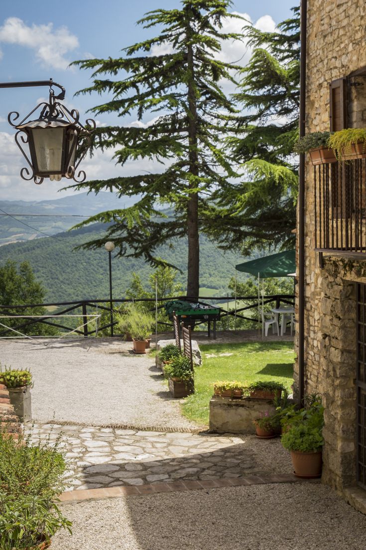 Angolo di un agriturismo circondato da vegetazione, con panorama sulle colline circostanti.
