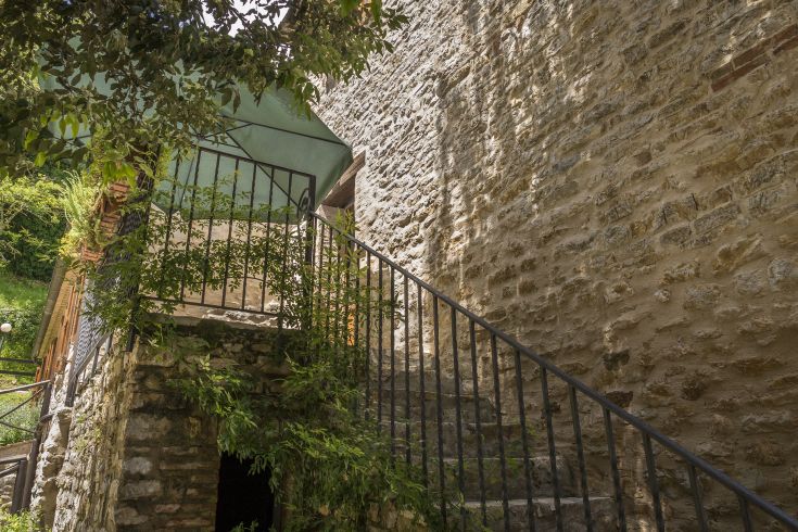 Scalinata che porta a un'area esterna, circondata da muretti di pietra e vegetazione.