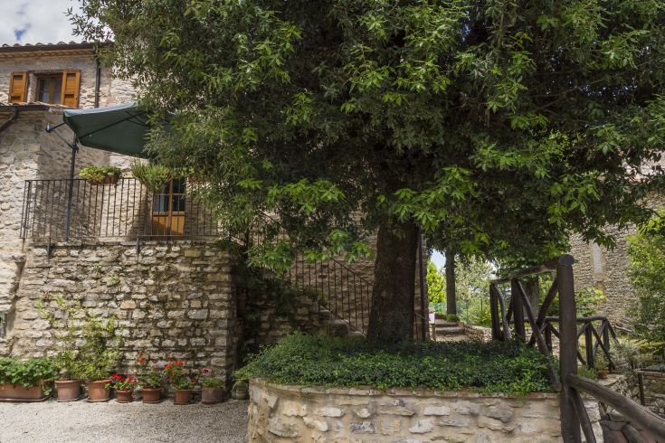 Scena di un agriturismo circondato dal verde, con un antico palazzo in pietra e aree all'aperto ben tenute.