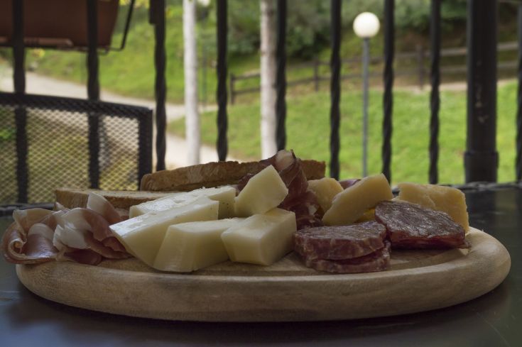 Un piatto con una selezione di salumi e formaggi, servito insieme a fette di pane, ideale per condividere convivialmente.