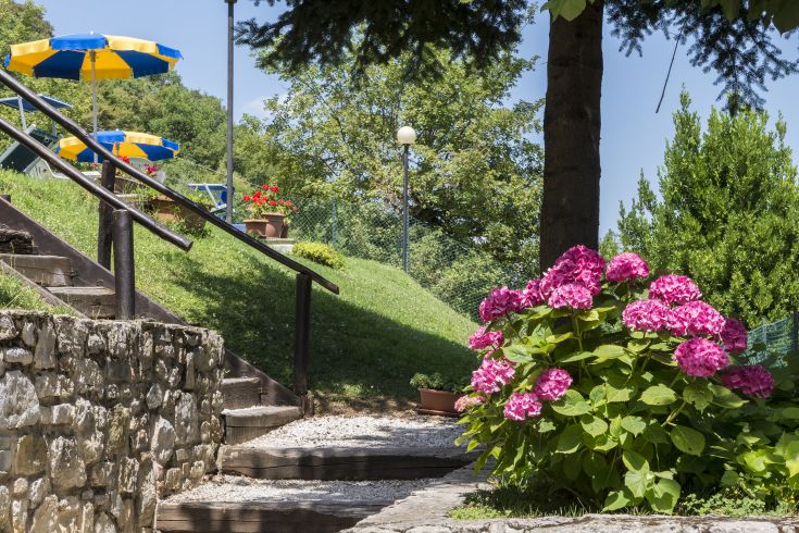 Un'area serena con fiori variopinti e ombrelloni, perfetta per godersi momenti di relax immersi nella natura.