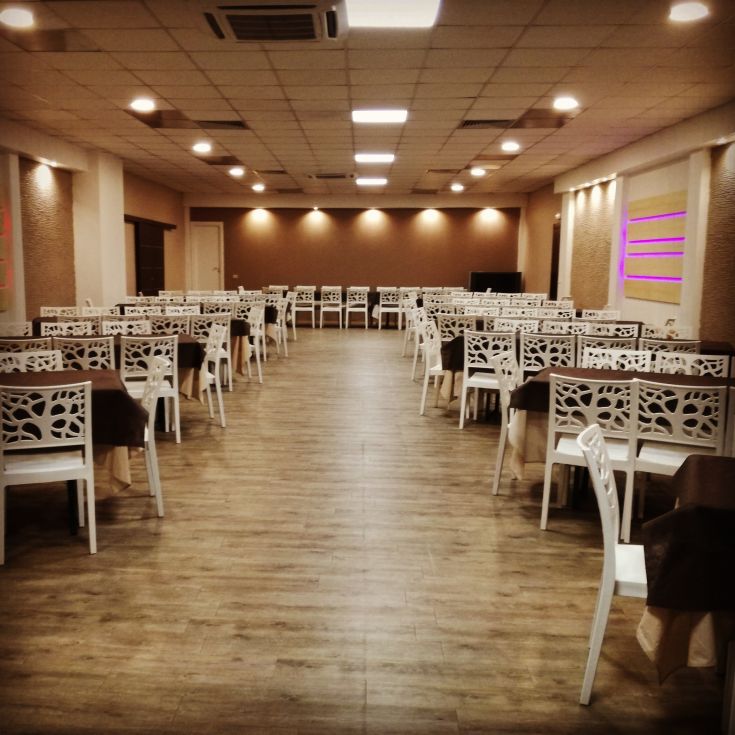 Interior of a restaurant with white tables and chairs, ready to welcome guests.
