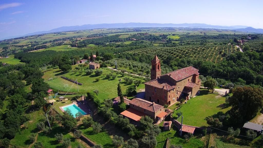 Overview of Ostello San Donato, surrounded by greenery, with views of the countryside and a swimming pool.