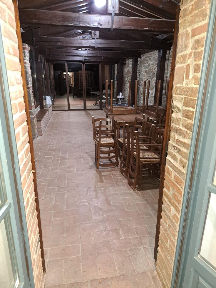 Spazio interno di un ostello con tavoli e sedie in legno, adatto per incontri o momenti di relax.