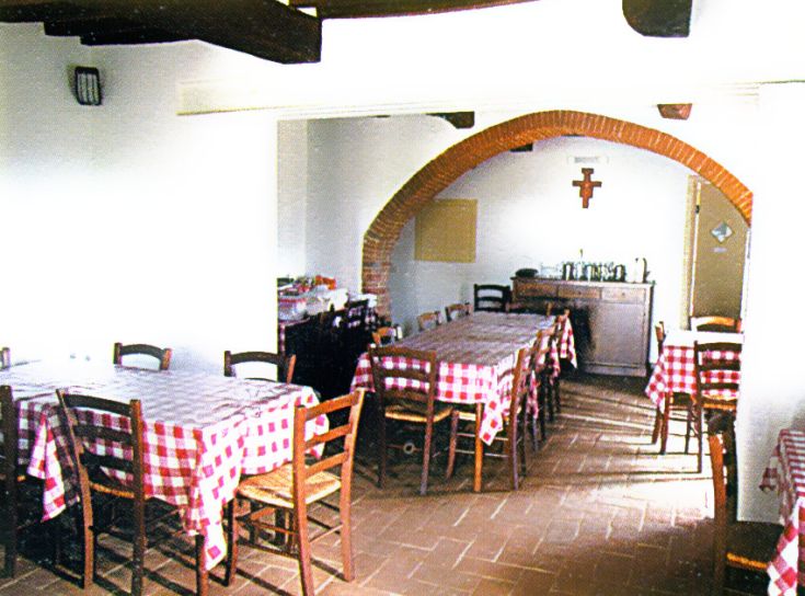 Spazio semplice e informale con tavoli a scacchi rossi e bianchi, ideale per pasti in compagnia.