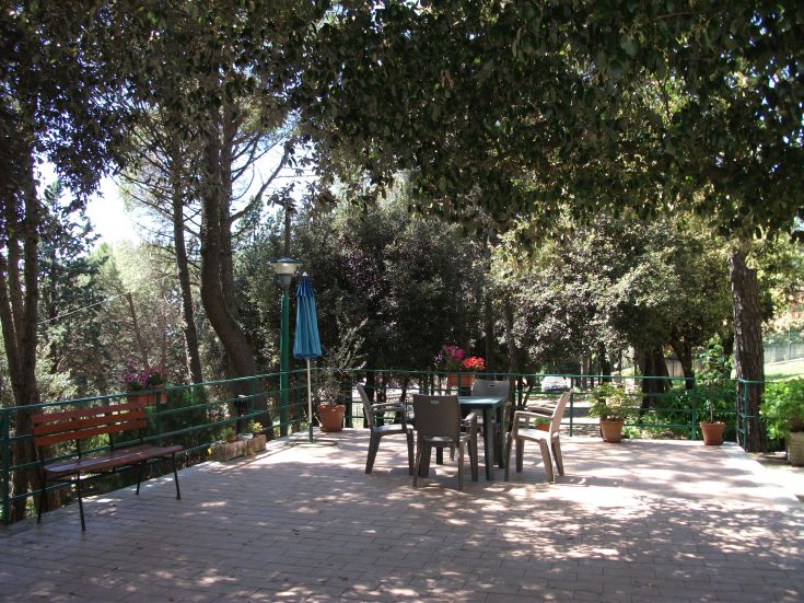 Terrace surrounded by greenery, furnished with a table and chairs. A peaceful place for relaxation.