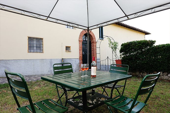 Ein einladender Außenbereich mit einem grünen Tisch und einer Flasche Wein, perfekt für entspannende Momente.