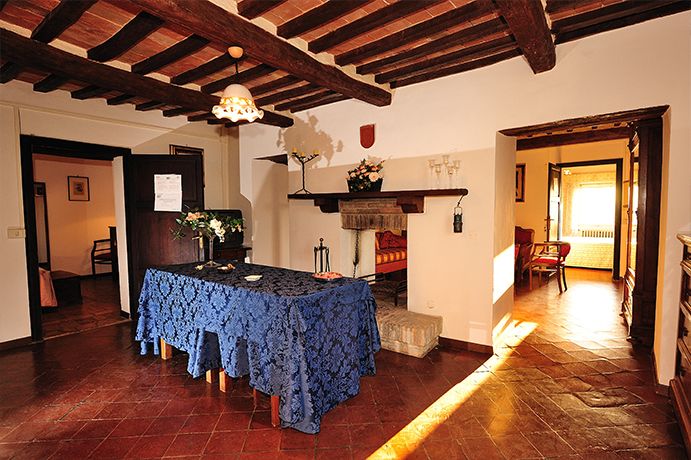 Helles Interieur mit einem schön gedeckten Tisch, sichtbaren Holzbalken und einem funktionierenden Kamin.