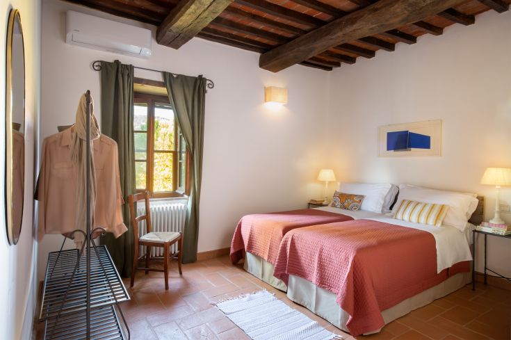 Chambre simple avec des lits simples, éclairage doux et vue sur la verdure environnante.