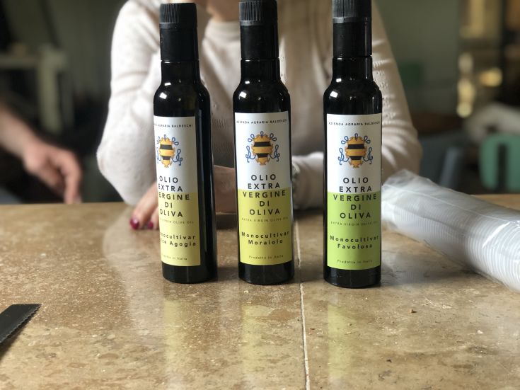 Trois bouteilles d'huile d'olive extra vierge de différents types disposées sur une table en marbre.