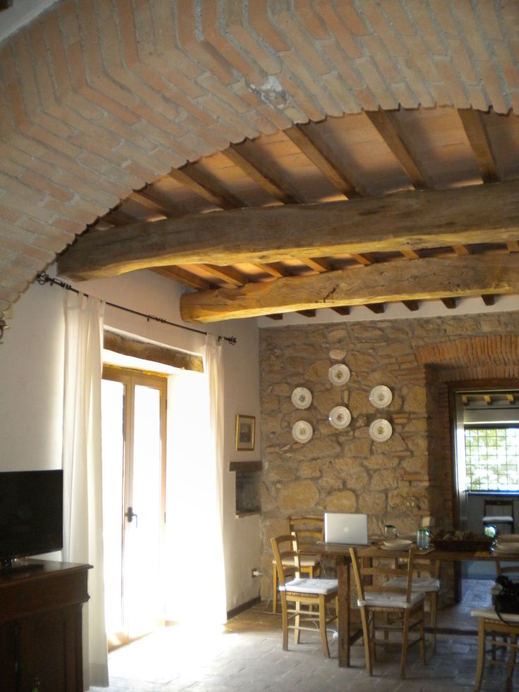 Interior of a renovated building with exposed beams, wooden furnishings, and large windows for natural light.