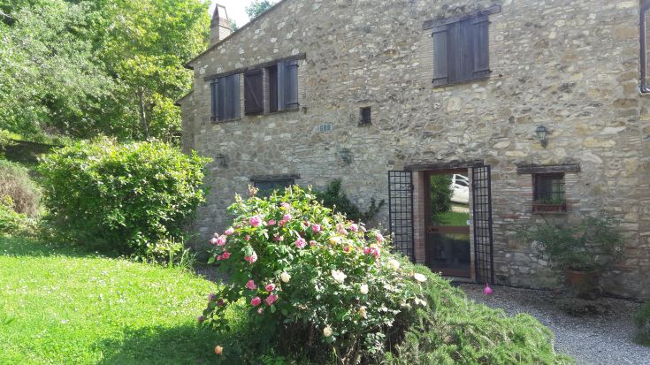 A stone farmhouse surrounded by a well-maintained garden and views of the surrounding fields.