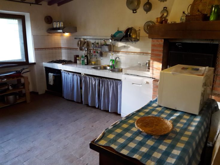 Spacious kitchen with a checkered table and wooden details. Natural light fills the simple space.