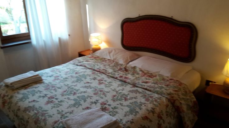 Cozy matrimonial room at 'Le Corone' palace, surrounded by trees in a tranquil setting.