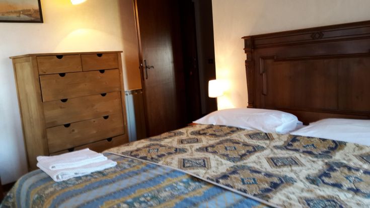 Cozy room with a wooden bed and dresser, lit by a warm-glow lamp.