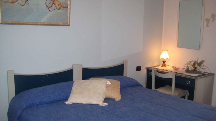 Spazio intimo con letto matrimoniale e mobilia essenziale, perfetto per un soggiorno rilassante.