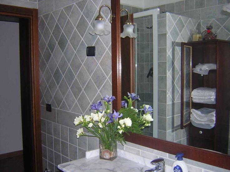 Un bagno con piastrelle in ceramica e un vaso di fiori freschi.