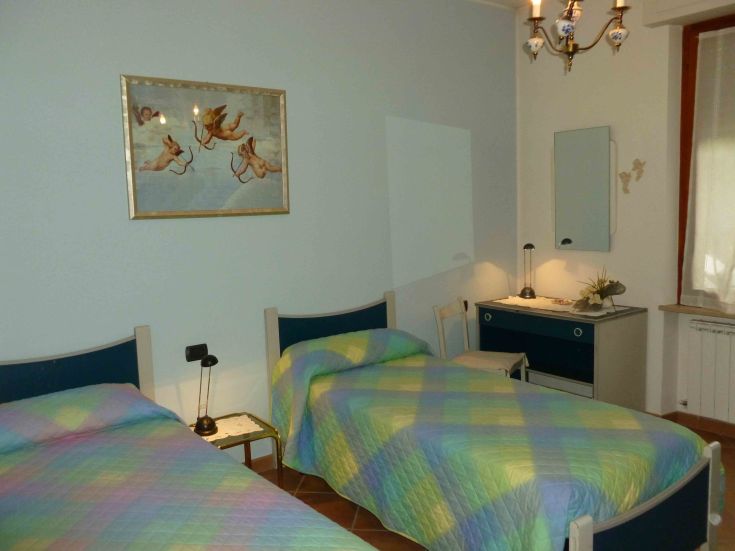 Stanza confortevole con letti singoli, arredata con tonalità leggere e decorazioni sulle pareti.