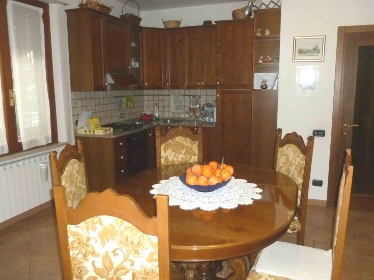 Una cucina semplice e confortevole, dotata di un tavolo in legno e frutta fresca, ideale per momenti in famiglia.