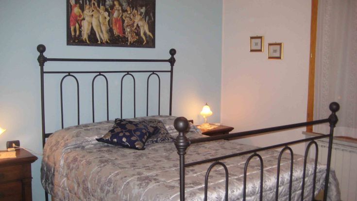 Camera accogliente con letto in ferro battuto, arredamento semplice e atmosfera rilassante.