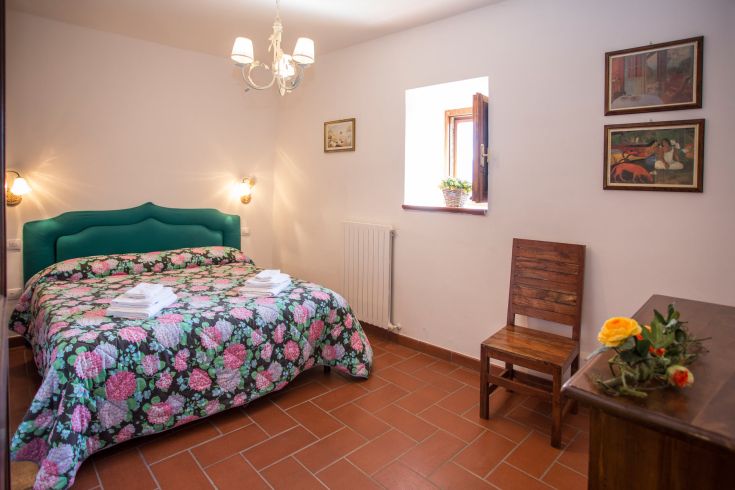 Simple and comfortable room with floral patterned bedding and wooden accents, ideal for moments of tranquility.