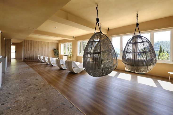 Ein heller Wellnessraum mit modernen Stühlen und Schaukeln, die eine entspannende Atmosphäre schaffen.