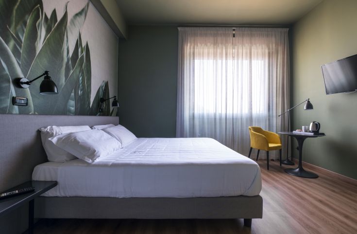 Gemütliches Hotelzimmer mit modernen Details, grünen Farbtönen und Blick auf eine ruhige Umgebung.