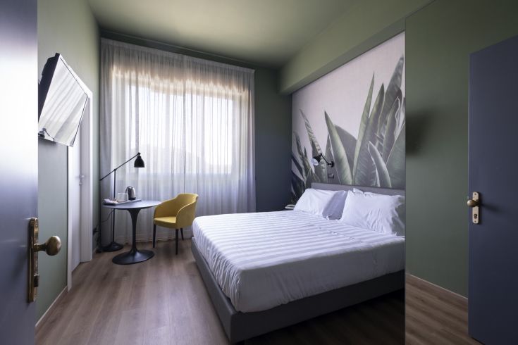 Moderne Hotelzimmer mit gemütlichem Stil und grünen Tönen, perfekt für einen ruhigen Aufenthalt.